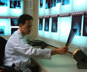 Picture of a male Medical Worker sitting down and holding an image on an X-ray.